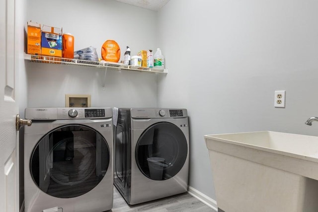 laundry room with laundry area, a sink, baseboards, light wood finished floors, and washer and clothes dryer