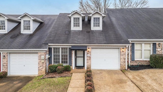 new england style home featuring driveway, an attached garage, and brick siding