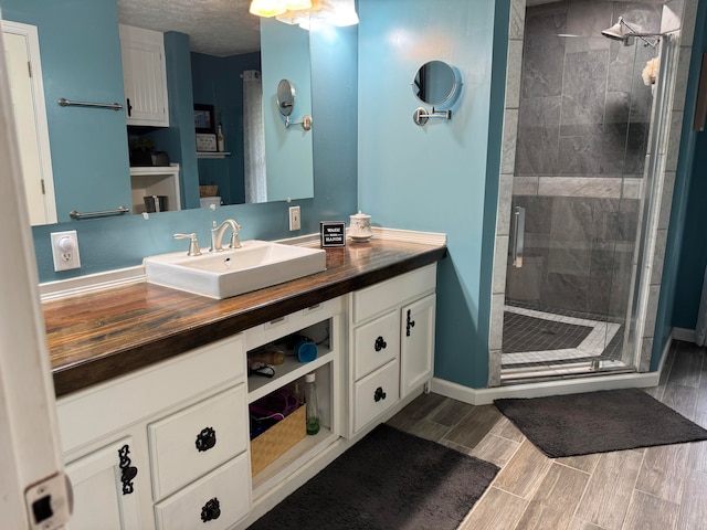 bathroom with vanity, a shower with door, and a textured ceiling