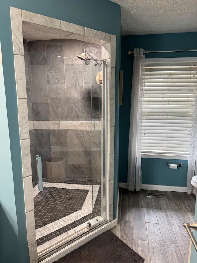 bathroom with toilet, an enclosed shower, wood-type flooring, and a textured ceiling