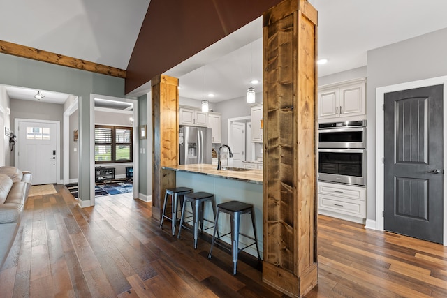 kitchen featuring appliances with stainless steel finishes, dark hardwood / wood-style flooring, light stone counters, decorative light fixtures, and white cabinets