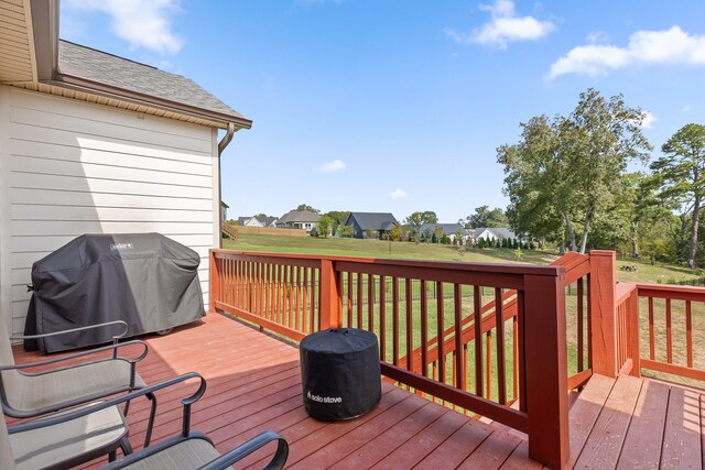 wooden terrace featuring a lawn and a grill