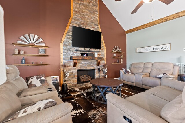 living room featuring high vaulted ceiling, ceiling fan, and a stone fireplace