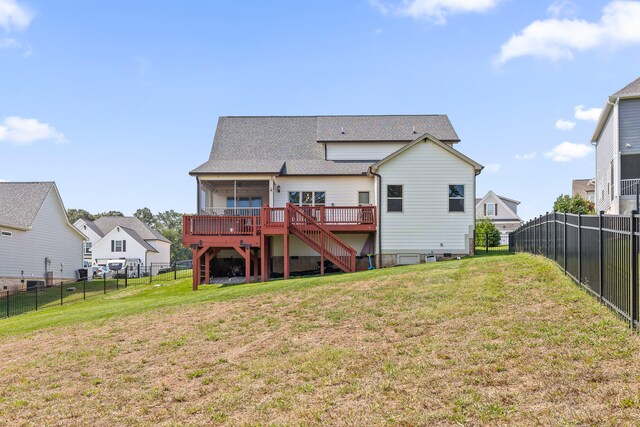 back of property with a wooden deck, a lawn, and a sunroom