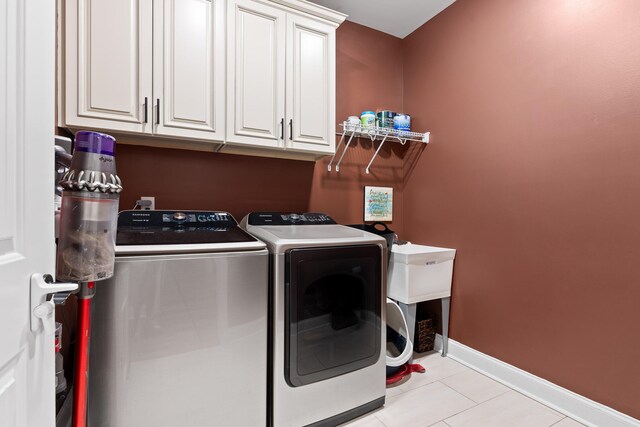 laundry room with cabinets, light tile patterned floors, and washing machine and clothes dryer