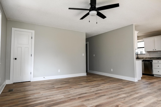 unfurnished living room featuring ceiling fan, a textured ceiling, and light hardwood / wood-style flooring