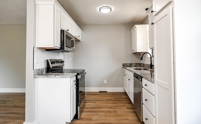 kitchen featuring sink, light stone counters, stainless steel appliances, decorative backsplash, and white cabinets