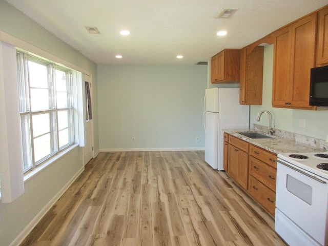 kitchen featuring sink, light stone counters, white appliances, and light wood-type flooring