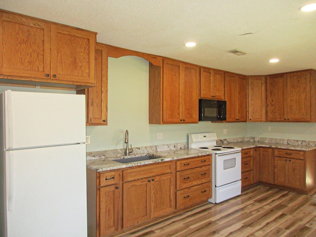 kitchen featuring sink, light stone counters, white appliances, and light hardwood / wood-style flooring