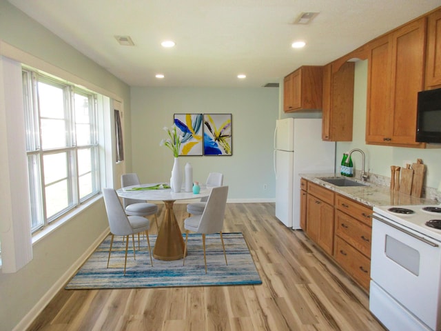 kitchen with light stone countertops, sink, white appliances, and light hardwood / wood-style floors