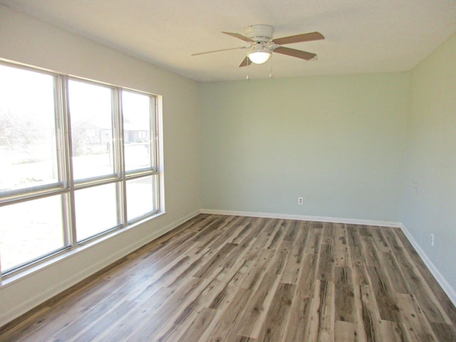 empty room featuring hardwood / wood-style flooring, a wealth of natural light, and ceiling fan