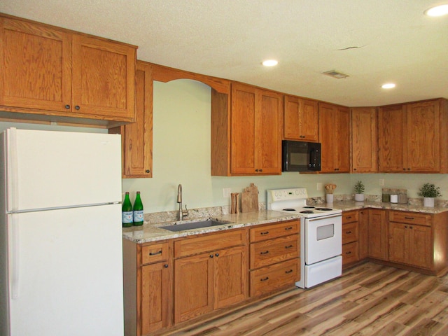 kitchen featuring sink, light stone counters, white appliances, and light wood-type flooring