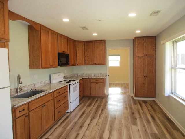 kitchen with light stone counters, sink, white appliances, and light hardwood / wood-style flooring