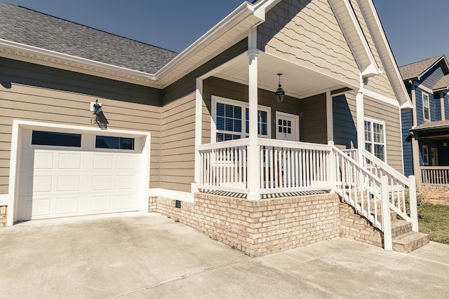 property entrance with a garage, covered porch, concrete driveway, and a shingled roof