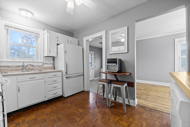 kitchen featuring sink, dark parquet flooring, white cabinets, and white fridge