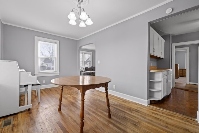 dining area featuring crown molding, an inviting chandelier, and light wood-type flooring