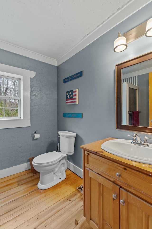 bathroom with crown molding, vanity, wood-type flooring, and toilet