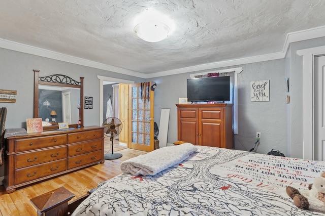 bedroom with a textured ceiling, light hardwood / wood-style floors, and crown molding