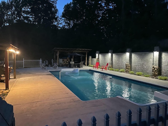 pool at night featuring a pergola, a water view, and a patio