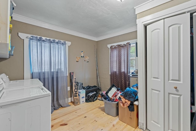 clothes washing area featuring wood-type flooring, washing machine and dryer, and crown molding