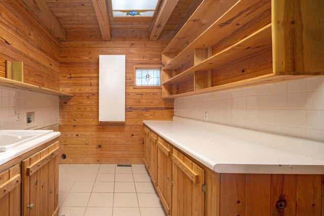 kitchen with a skylight, wood ceiling, wooden walls, light tile patterned floors, and beamed ceiling