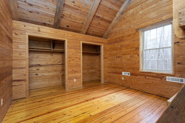 unfurnished bedroom featuring vaulted ceiling with beams, wooden walls, wood ceiling, and light wood-type flooring