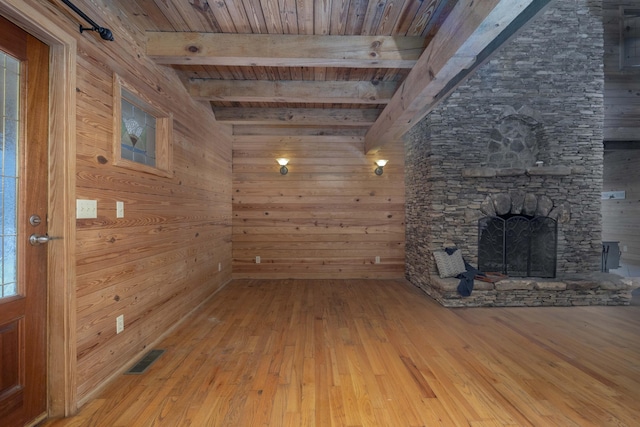 unfurnished living room featuring beam ceiling, wood walls, wood ceiling, and hardwood / wood-style flooring