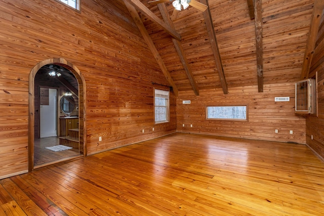 unfurnished living room with vaulted ceiling with beams, wood walls, light hardwood / wood-style flooring, and wooden ceiling