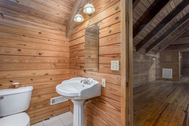 bathroom featuring wooden walls, lofted ceiling with beams, toilet, and wooden ceiling