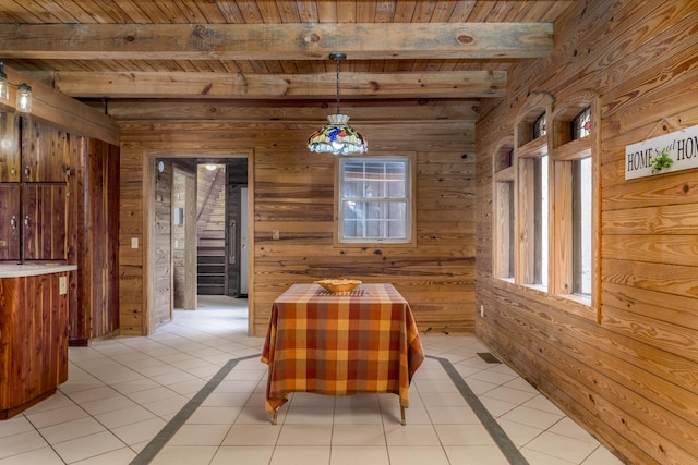 unfurnished dining area featuring beam ceiling, wooden walls, and light tile patterned floors