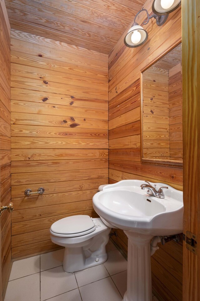 bathroom with toilet, tile patterned floors, wooden walls, and wood ceiling