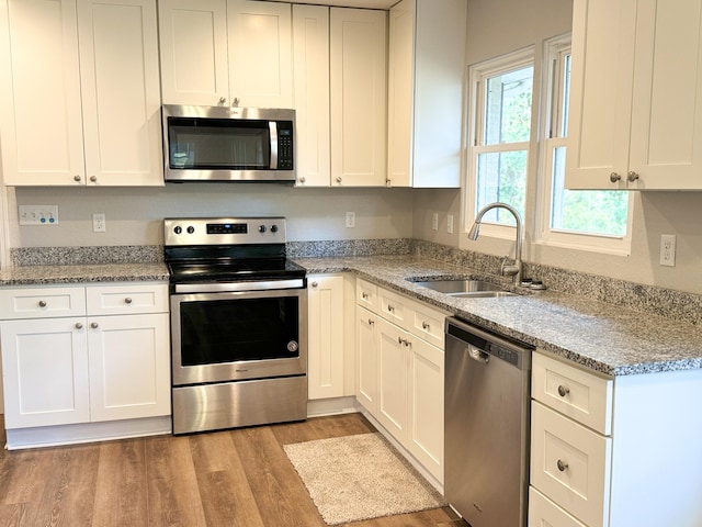 kitchen featuring white cabinetry, light stone countertops, light wood-type flooring, and appliances with stainless steel finishes