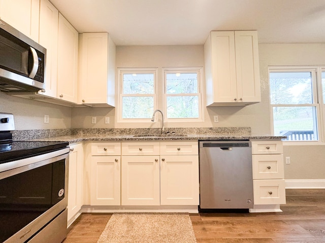 kitchen with appliances with stainless steel finishes, light hardwood / wood-style flooring, plenty of natural light, and sink