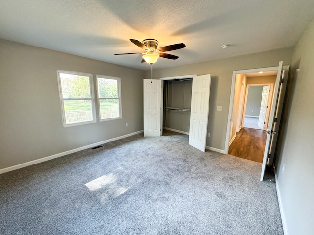 unfurnished bedroom featuring ceiling fan, a closet, carpet floors, and a textured ceiling