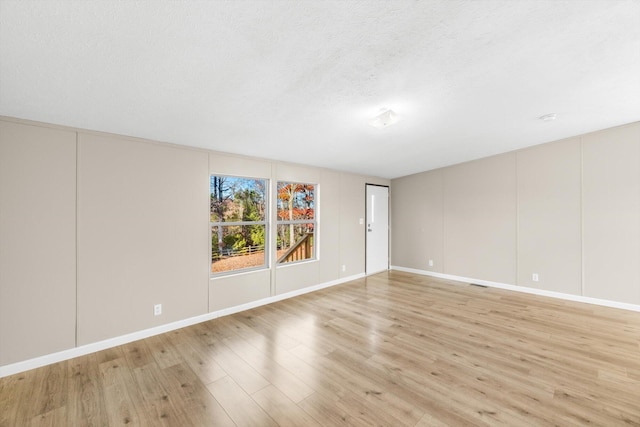 unfurnished room with a textured ceiling and light hardwood / wood-style flooring