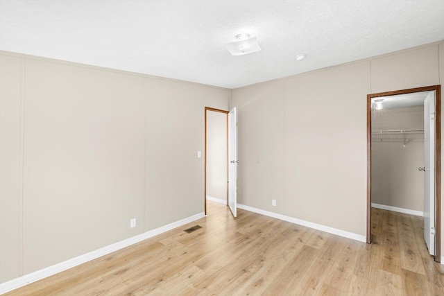 unfurnished bedroom with light wood-type flooring, a textured ceiling, and a closet
