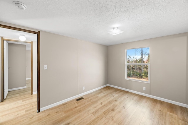 unfurnished room with a textured ceiling and light hardwood / wood-style flooring