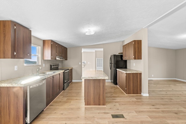 kitchen featuring a center island, lofted ceiling, sink, light hardwood / wood-style floors, and stainless steel appliances
