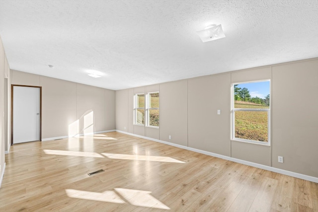 empty room with light hardwood / wood-style floors, a textured ceiling, and basketball court