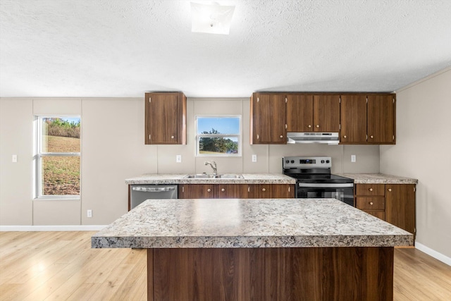 kitchen with sink, stainless steel appliances, a textured ceiling, and light hardwood / wood-style floors