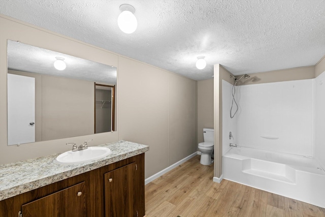 full bathroom featuring toilet, vanity, a textured ceiling, and hardwood / wood-style flooring