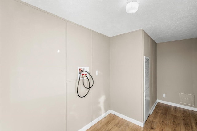 clothes washing area with hardwood / wood-style floors, washer hookup, and a textured ceiling