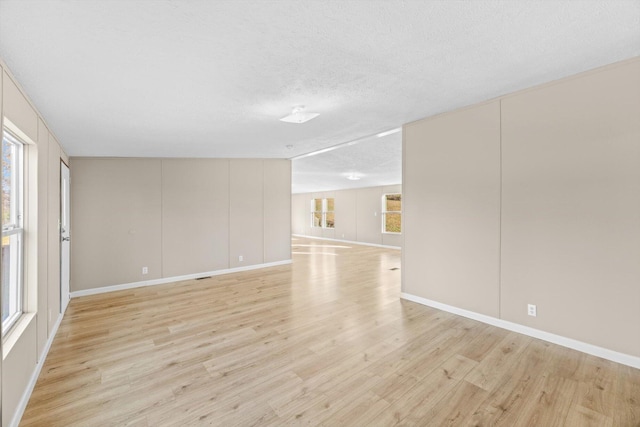 empty room with a textured ceiling and light hardwood / wood-style floors