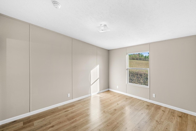 spare room with light hardwood / wood-style floors and a textured ceiling