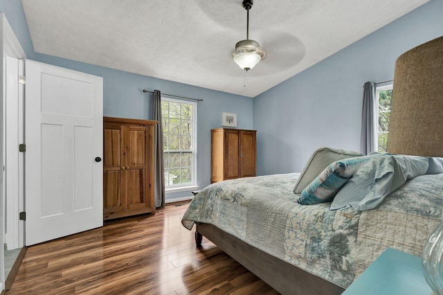 bedroom with a textured ceiling, wood finished floors, and ceiling fan