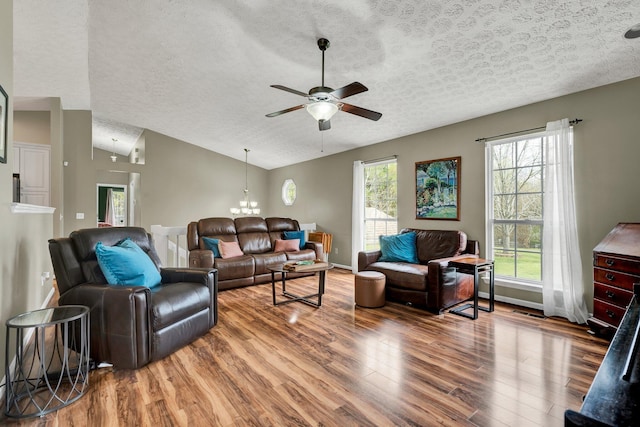 living area with a ceiling fan, plenty of natural light, vaulted ceiling, and wood finished floors