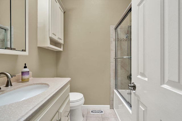 bathroom featuring vanity, toilet, combined bath / shower with glass door, tile patterned floors, and baseboards