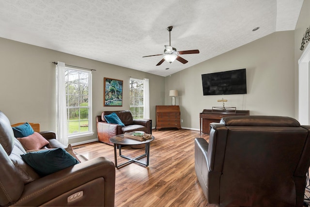 living room featuring baseboards, vaulted ceiling, a textured ceiling, ceiling fan, and wood finished floors
