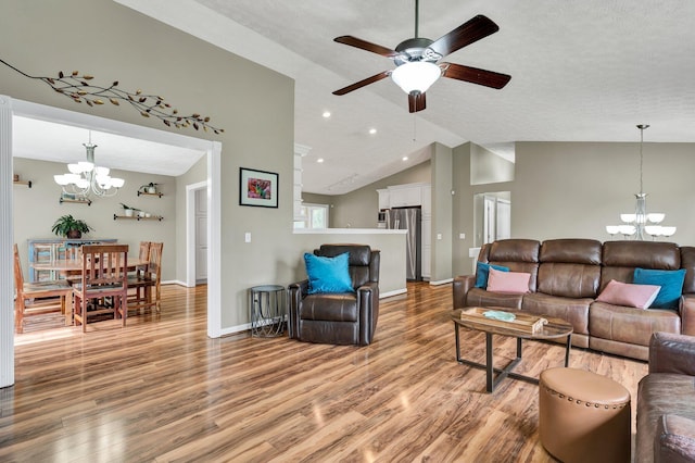 living area featuring wood finished floors, ceiling fan with notable chandelier, baseboards, and lofted ceiling