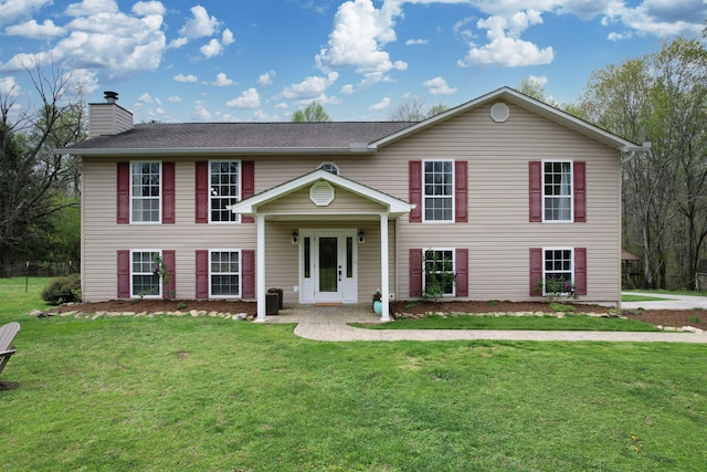 split foyer home featuring a chimney, a shingled roof, and a front lawn